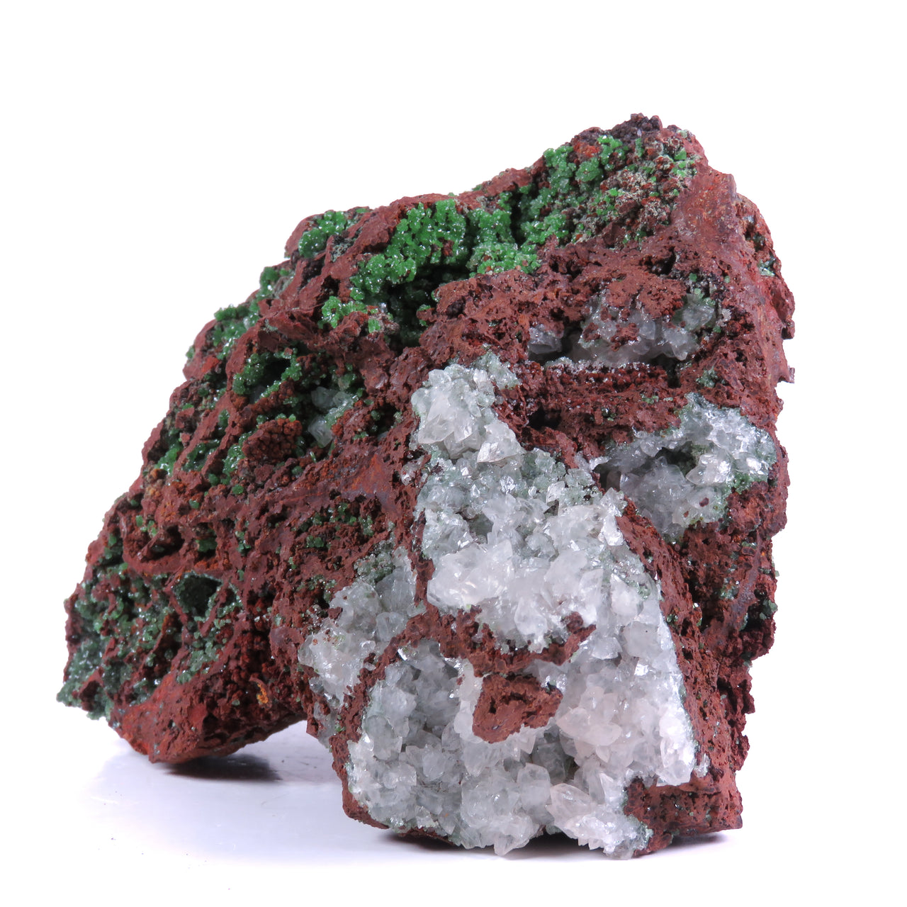 A mineral specimen featuring bright green cuprian adamite crystals nestled within symmetrical vugs (cavities) in red-brown host rock. Well-formed white calcite crystals are visible to one side. The reverse side displays more elongated, subtly-colored cuprian austinite crystals. The overall banding pattern of the crystal-filled pockets creates a symmetrical appearance across the specimen.