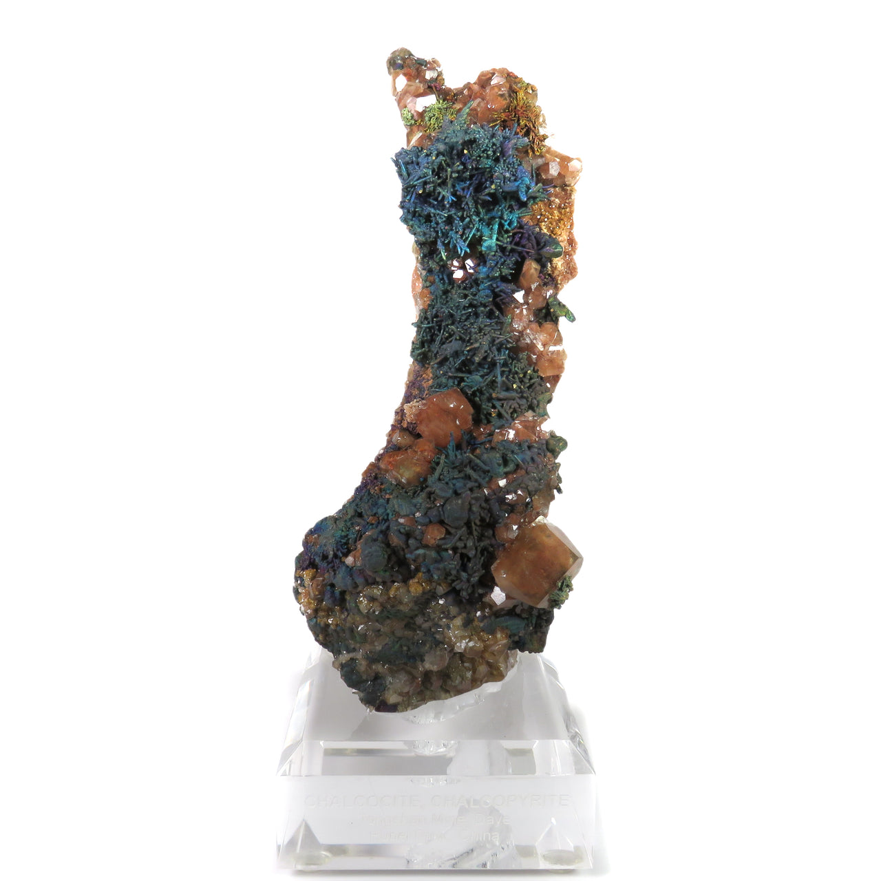 A dramatic, tower-like mineral specimen featuring iridescent blue-green chalcopyrite forming organic, tendril-like patterns across the surface. Orange-red calcite crystals are scattered throughout, creating striking contrast against the metallic sulfide minerals. The specimen's unusual formation creates a sculptural presence, with layered minerals building up to create a distinctive vertical form.